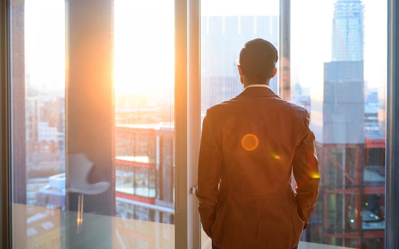 Person looking through a window with a sunset shining on their face